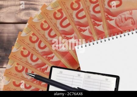 50 Kanadische Dollar Scheine Fächer und Notizblock mit Kontaktbuch und schwarzem Stift. Konzept der Finanzplanung und Geschäftsstrategie. Rechnungslegung und Investitionen Stockfoto