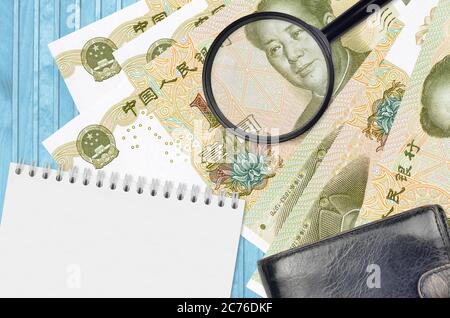 1 chinesische Yuan-Scheine und Lupe mit schwarzem Geldbeutel und Notizblock. Konzept von gefälschtem Geld. Suchen Sie nach Unterschieden in Details zu Geldrechnungen Stockfoto