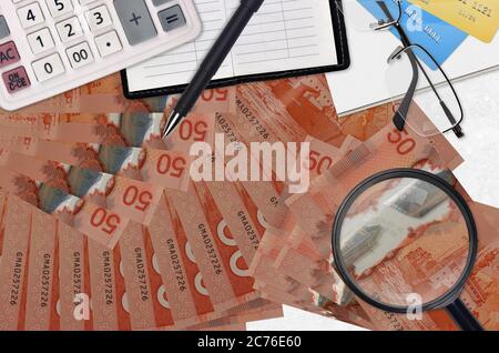 50 kanadische Dollar Rechnungen und Rechner mit Brille und Stift. Tax Payment Saison Konzept oder Investment-Lösungen. Suche nach einem Job mit hohem Gehalt EA Stockfoto
