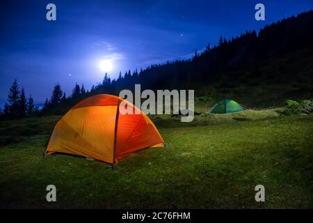 Zwei leuchtend Orange und grün camping Zelte unter Mond, Sterne in der Nacht Stockfoto