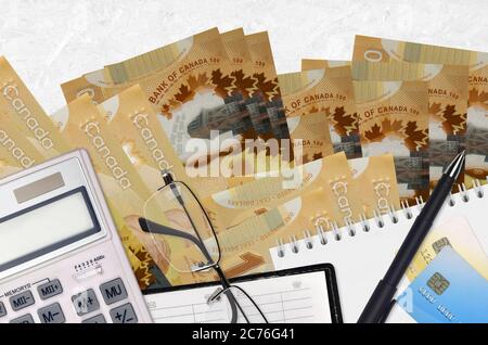 100 kanadische Dollar Rechnungen und Rechner mit Brille und Stift. Tax Payment Saison Konzept oder Investment-Lösungen. Finanzplanung oder Buchhalter p Stockfoto