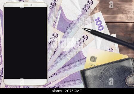100 philippinische Piso Rechnungen und Smartphone mit Geldbörse und Kreditkarte. E-Payment oder E-Commerce-Konzept. Online-Shopping und Geschäft mit tragbaren devi Stockfoto