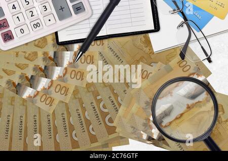 100 kanadische Dollar Rechnungen und Rechner mit Brille und Stift. Tax Payment Saison Konzept oder Investment-Lösungen. Suche nach einem Job mit hohem Gehalt e Stockfoto