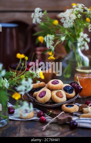 Daumendruck Mandelplätzchen mit Marmelade auf rustikalem Holzhintergrund Stockfoto