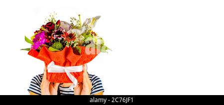 Frau versteckt ihr Gesicht hinter dem Korb von Röschen. Frauen Hände halten bunte Blumenstrauß. Zusammensetzung von verschiedenen Blumen in Wickelkorb auf Stockfoto