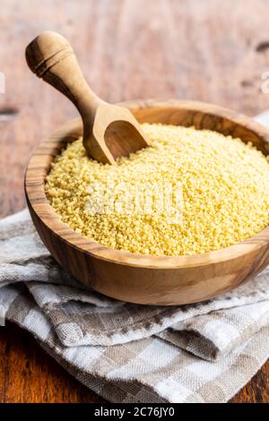 Getrocknete gelbe Couscous in Holzschale und Holzlöffel. Stockfoto