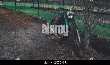 Stary Oskol, Russland 25. Januar 2019: Altes rostiges Motorrad in der Nähe von Zaun auf dem Boden. Nahaufnahme von verlassenen defekten Motorrad. Stockfoto