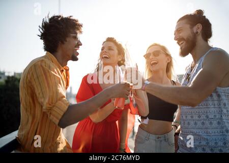 Eine Gruppe glücklicher Freunde, die aushangelt sind und Getränke genießen, Festival Stockfoto