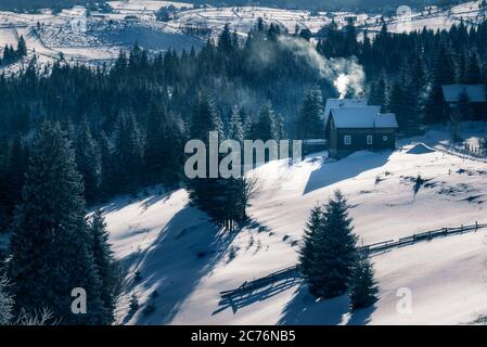 Kleine Häuser mit Rauch im Kamin an einem kalten Wintermorgen in Marisel, Cluj County, Siebenbürgen Region, Rumänien Stockfoto