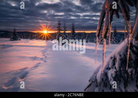 Schöner Sonnenuntergang im Winter auf der Spitze der Berge mit Fußabdrücken gehen in Richtung der untergehenden Sonne in der Nähe von Marisel, Cluj County, Siebenbürgen Region, Roman Stockfoto