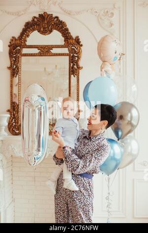 Porträt einer lächelnden Frau, die ihren Enkel an seinem 1. Geburtstag hält Stockfoto