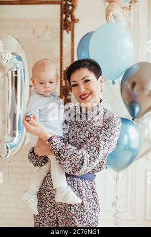 Porträt einer lächelnden Frau, die ihren Enkel an seinem 1. Geburtstag hält Stockfoto