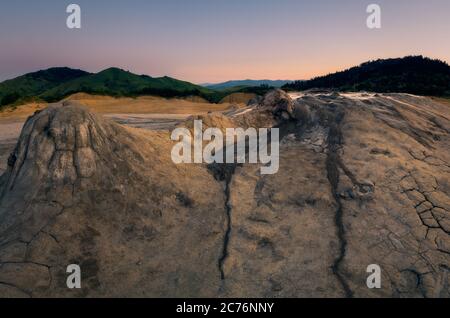 Panoramabild einiger Krater bei den Muddy Volcanoes in Rumänien, Buzau County mit den Bergen im Hintergrund vor klarem Himmel Stockfoto