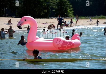 Acworth, GA, USA. Juli 2020. Schwimmer spielen mit einem großen aufgeblasenen Flamingo in der einzigen sicheren Zone für Schwimmer am GaltÃs Ferry Beach am See Altoona in Acworth. Der Strand wird vom U.S. Army Corps of Engineers betrieben. Quelle: Robin Rayne/ZUMA Wire/Alamy Live News Stockfoto