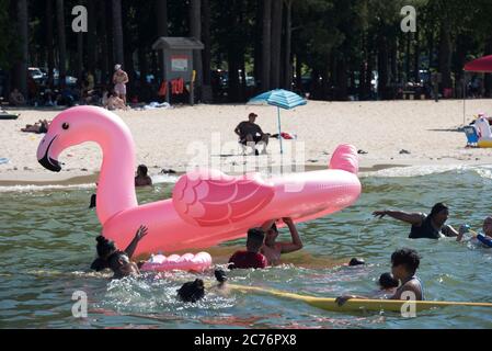 Acworth, GA, USA. Juli 2020. Schwimmer spielen mit einem großen aufgeblasenen Flamingo in der einzigen sicheren Zone für Schwimmer am GaltÃs Ferry Beach am See Altoona in Acworth. Der Strand wird vom U.S. Army Corps of Engineers betrieben. Quelle: Robin Rayne/ZUMA Wire/Alamy Live News Stockfoto