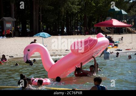 Acworth, GA, USA. Juli 2020. Schwimmer spielen mit einem großen aufgeblasenen Flamingo in der einzigen sicheren Zone für Schwimmer am GaltÃs Ferry Beach am See Altoona in Acworth. Der Strand wird vom U.S. Army Corps of Engineers betrieben. Quelle: Robin Rayne/ZUMA Wire/Alamy Live News Stockfoto