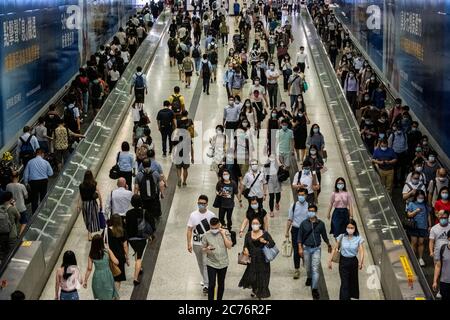 Passagiere mit Schutzmasken gehen durch die Hong Kong Station.die Regierung von Hongkong erlegt neue strenge soziale Distanzierungsmaßnahmen und das obligatorische Tragen von Gesichtsmasken für Menschen, die öffentliche Verkehrsmittel benutzen. Stockfoto