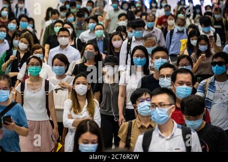 Passagiere mit Schutzmasken gehen durch die Hong Kong Station.die Regierung von Hongkong erlegt neue strenge soziale Distanzierungsmaßnahmen und das obligatorische Tragen von Gesichtsmasken für Menschen, die öffentliche Verkehrsmittel benutzen. Stockfoto