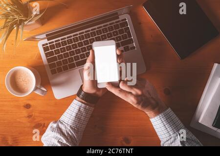 Smartphone-Modell oben Aufnahme, Geschäftsmann hält Handy mit leerem Bildschirm über Schreibtisch und Laptop-Computer Stockfoto