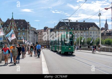Basel, BL / Schweiz - 8. Juli 2020: Passanten überqueren den Rhein nach Klein Basel mit der Basler Straßenbahn vorbei Stockfoto