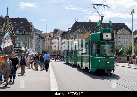 Basel, BL / Schweiz - 8. Juli 2020: Passanten überqueren den Rhein nach Klein Basel mit der Basler Straßenbahn vorbei Stockfoto