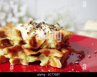 Zucchini Waffeln auf einem roten Teller mit Sauce und Gewürzen. Lebensmittelkonzept. Stockfoto