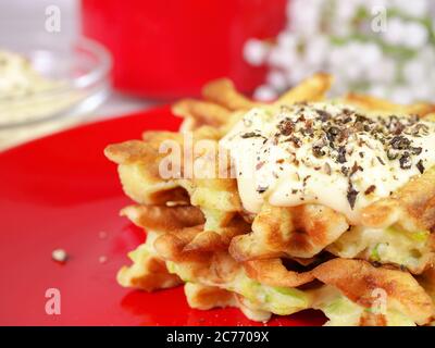 Zucchini Waffeln auf einem roten Teller mit Sauce und Gewürzen. Lebensmittelkonzept. Stockfoto