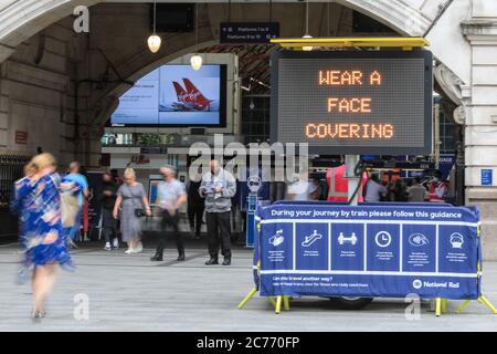 Westminster, London, Großbritannien. Juli 2020. Ein großes Schild und engagiertes Personal erinnern Pendler daran, eine Gesichtsbedeckung am Bahnhof Victoria zu tragen. Gesichtsmasken sind bereits obligatorisch auf öffentlichen Verkehrsmitteln, und ein auch in Geschäften und Supermärkten ab dem 24. Juli in England erforderlich. Kredit: Imageplotter/Alamy Live Nachrichten Stockfoto