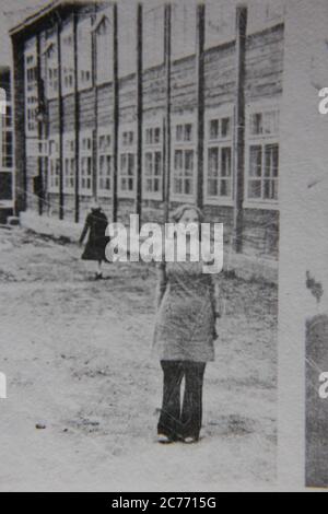 Feine 70er Jahre Vintage schwarz-weiß Lifestyle Fotografie einer Frau vor einem institutionellen Gebäude stehen. Stockfoto