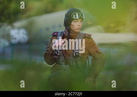 Eine junge Pilotin in Uniform der sowjetischen Armee Piloten während des Zweiten Weltkriegs Militär-Shirt mit Schulterriemen eines Major, Fallschirm, Flug helme Stockfoto