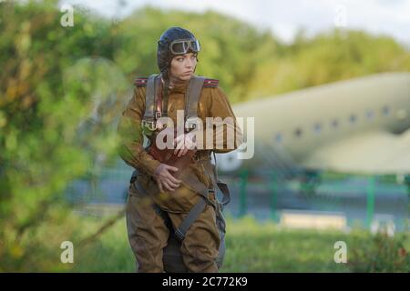 Eine junge Pilotin in Uniform der sowjetischen Armee Piloten während des Zweiten Weltkriegs Militär-Shirt mit Schulterriemen eines Major, Fallschirm, Flug helme Stockfoto