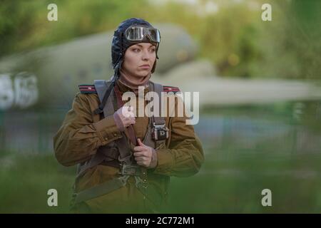 Eine junge Pilotin in Uniform der sowjetischen Armee Piloten während des Zweiten Weltkriegs Militär-Shirt mit Schulterriemen eines Major, Fallschirm, Flug helme Stockfoto