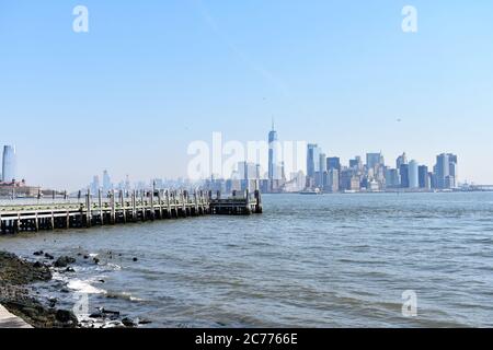 Ein stilles Pier auf Liberty Island. Die Skyline der Innenstadt und das World Trade Center sind vor einem klaren blauen Himmel zu sehen. Speicherplatz kopieren. Stockfoto