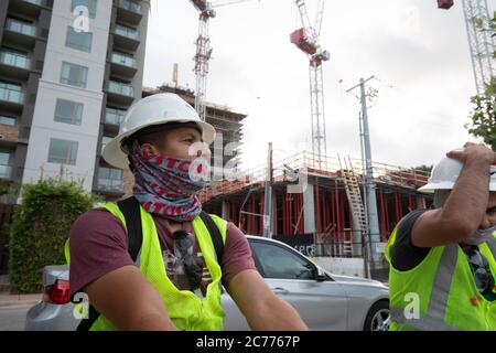 Austin, TX USA 14. Juli 2020: Bauarbeiter hören sich Sicherheitsunterweisungen an, während sie sich auf eine achtstündige Schicht in der 105-Grad-Hitze von Texas vorbereiten. Die Crews befinden sich im zweiten Stock eines geplanten 53-stöckigen Gebäudes, um Vorkehrungen gegen die Coronavirus-Pandemie zu treffen. Stockfoto