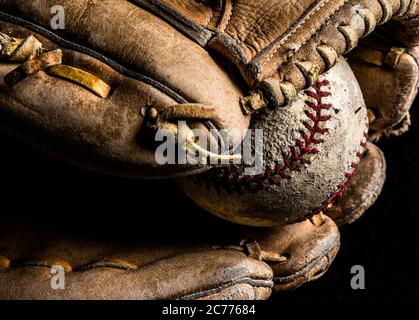 Baseballhandschuh hält einen abgewetzten alten Baseball. Stockfoto