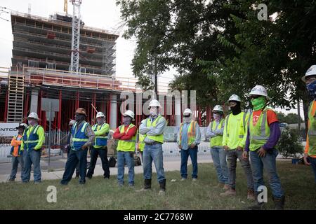 Austin, TX USA 14. Juli 2020: Bauarbeiter hören sich Sicherheitsunterweisungen an, während sie sich auf eine achtstündige Schicht in der 105-Grad-Hitze von Texas vorbereiten. Die Crews befinden sich im zweiten Stock eines geplanten 53-stöckigen Gebäudes, um Vorkehrungen gegen die Coronavirus-Pandemie zu treffen. Stockfoto