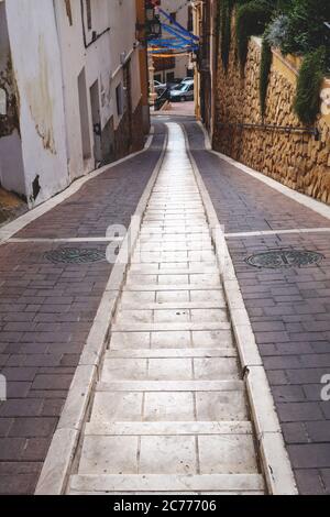 Polop de Marina, Costa Blanca, Spanien - 3. Oktober 2019: Schmale Gasse mit zwei Gleisen für Autoräder und Marmortreppen in der Mitte Stockfoto