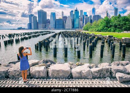 New York Tourist Frau, die mobile Foto mit dem Smartphone. Manhattan City Skyline Waterfront Lifestyle. Leute, die zu Fuß gehen und die Aussicht auf die Innenstadt genießen Stockfoto