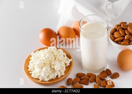 Proteinreiche Lebensmittel auf weißem Hintergrund - Hüttenkäse, Eier, Nüsse. Eine Reihe von gesunden Lebensmitteln für eine ausgewogene Ernährung. Stockfoto