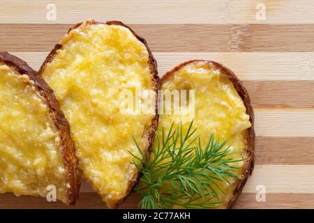 Heiße Sandwiches mit geschmolzenem Käse und Kräutern auf Holzgrund Stockfoto