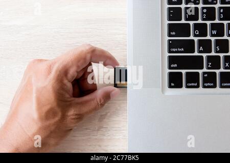 Speicherkarte von Hand in den Laptop-Steckplatz einsetzen Stockfoto