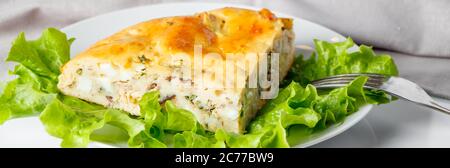 Leckere Fischkuchen auf einem Teller. Ein Stück Kuchen mit Makrele und Grüns auf weißem Hintergrund. Stockfoto