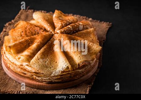 Ein Stapel köstlicher Pfannkuchen auf schwarzem Hintergrund. Essen für den Urlaub Maslenitsa. Platzieren Sie Ihren Text. Stockfoto