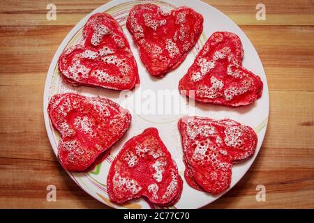 Rote herzförmige Pfannkuchen mit Liebe für Valentinstag und Tulpen auf Holzhintergrund gemacht Stockfoto