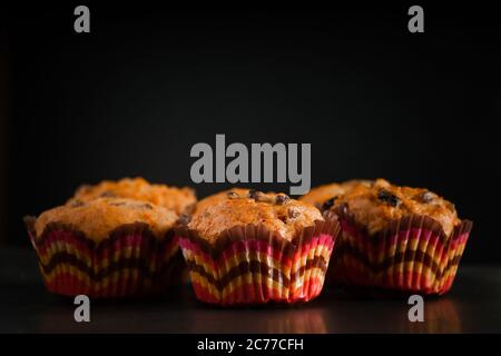 Appetitliche Muffins auf schwarzem Hintergrund. Süße hausgemachte Rosinenkuchen. Stockfoto