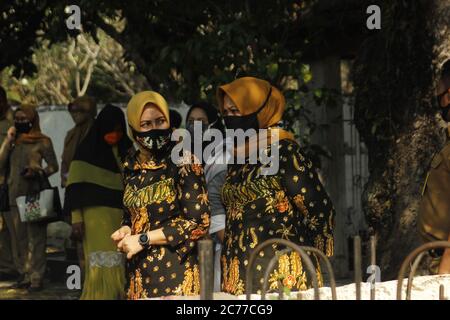 Leiterin des Madiun Regency Family Welfare Empowerment Mover Teams, Frau Penta Lianawati Ahmad Dawami [Mitte] begleitet von der stellvertretenden Vorsitzenden des Family Welfare Empowerment Teams, Frau Erni Hari Wuryanto [rechts von Mitte] in Batikkleidung und Masken typisch für Madiun Regency im Bereich des Stadtparkgrabes Madiun. Jedes Mal vor dem Jahrestag der Madiun Regency, datiert vom 18. Juli, nahm die Frau des Regenten und stellvertretenden Regenten von Madiun an einer Pilgertradition zu den Gräbern der Vorfahren, den ehemaligen Madiun Regenten Teil. (Foto von Ajun Ally/Pacific Press) Stockfoto