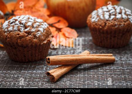 Schokoladen-Muffins mit Apfelfüllung auf einem Hintergrund aus Herbstblättern und Zimt Stockfoto