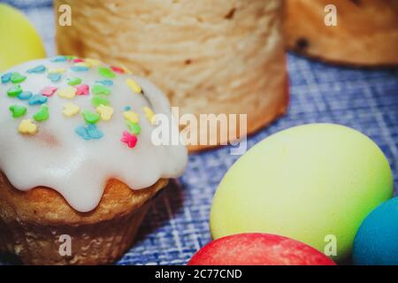 Festliche Komposition - Osterkuchen mit süßem Glasur und bemalten Eiern auf blauem Hintergrund. Stockfoto