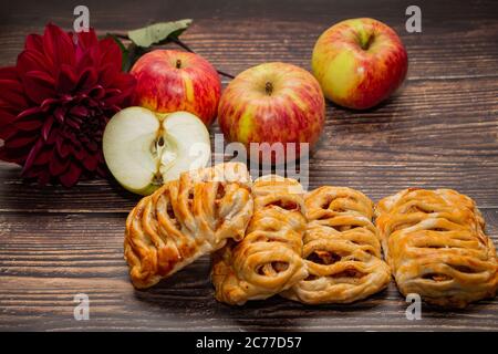 Hausgemachte Apfelkuchen mit süßer Füllung auf einem Hintergrund von Früchten und Blumen Stockfoto