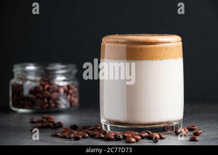 Eisgekühlter Dalgona-Kaffee auf dunkelgrauem Hintergrund. Ein Glas trendigen koreanischen Drink. Milch und süßer, flauschiger Schaum. Stockfoto